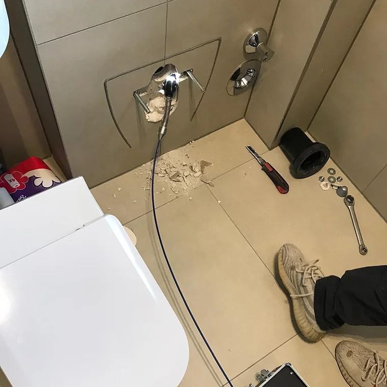 Kamerakabel führt durch eine Wandöffnung hinter einem Hänge-WC ins Rohr